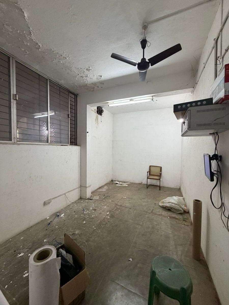 The empty Book Room with peeling ceiling plaster, an old fan and a bare cement floor