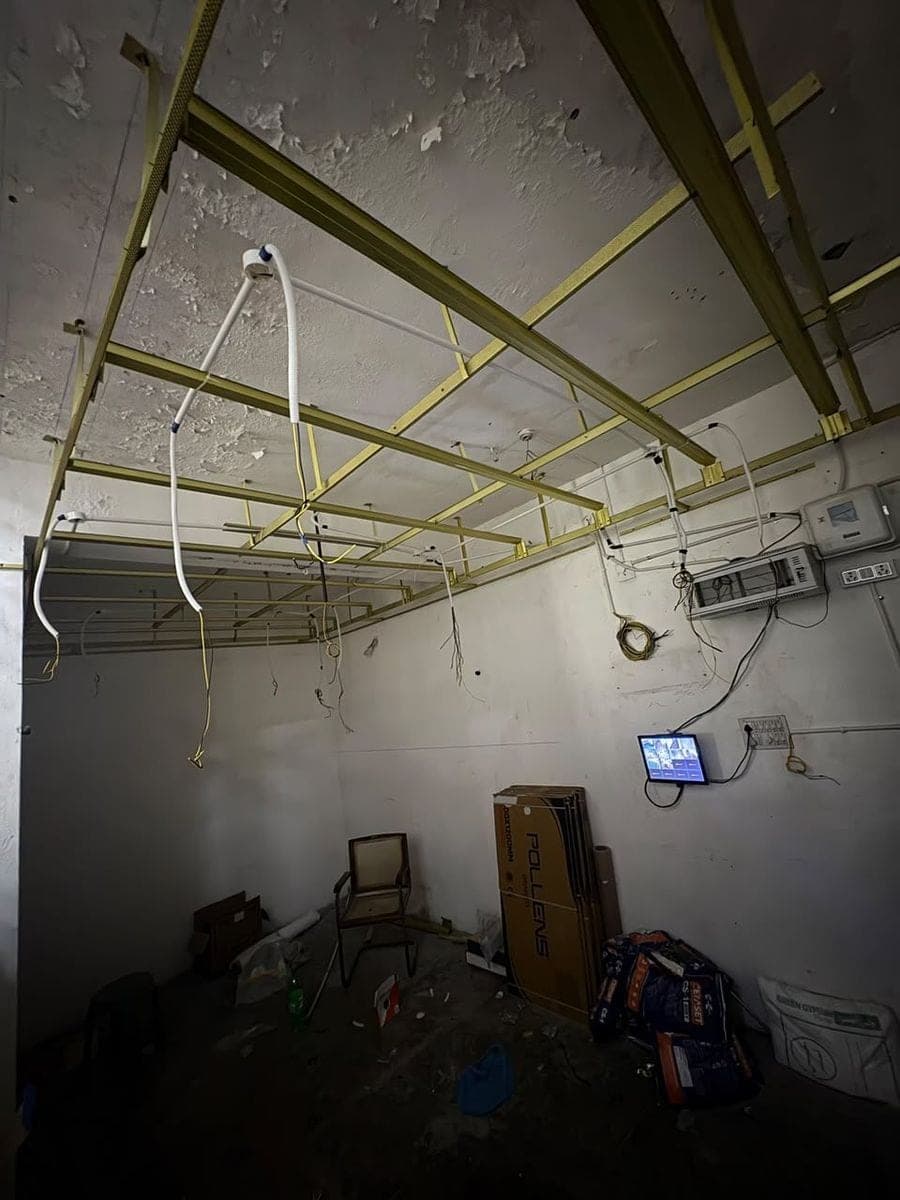 The metal frame of the false ceiling with new electrical conduits hanging from it