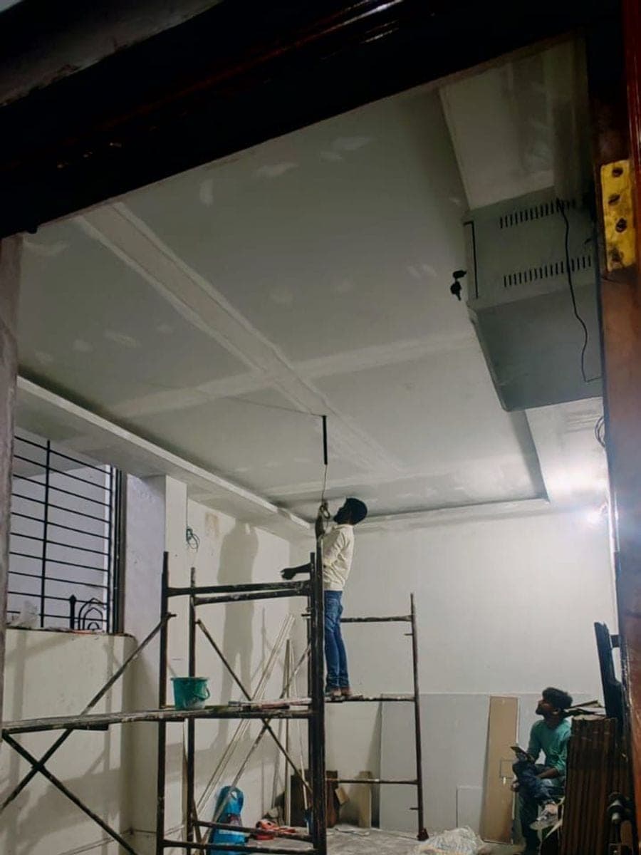 The new plain false ceiling boarded across the room, with a worker on scaffolding